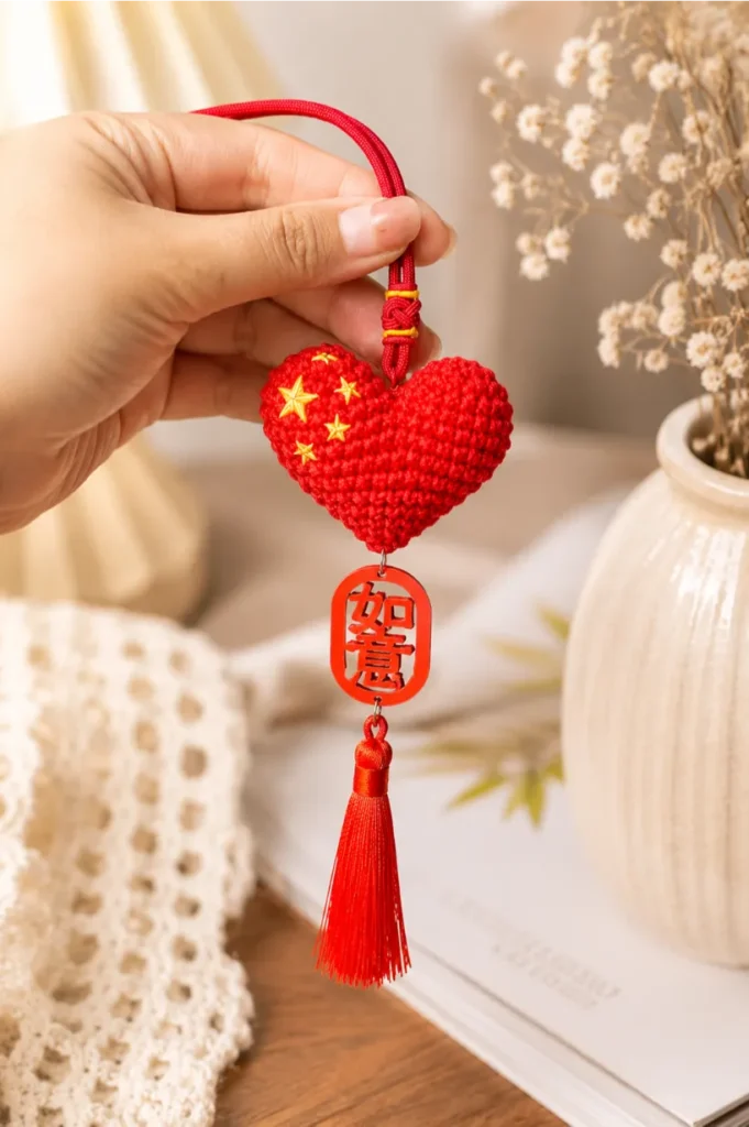 Best Small Crochet Projects for Beginners 12 Collection-style crochet heart phone charm displayed in a cozy handmade crochet setting, featuring a red crochet heart accessory with tassel and aesthetic handmade details.